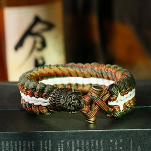 Dettaglio della fibbia a teschio sul braccialetto camouflage in paracord