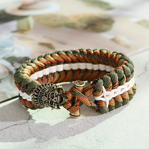 Dettaglio macro del braccialetto in paracord mimetico con ciondolo a testa di leone
