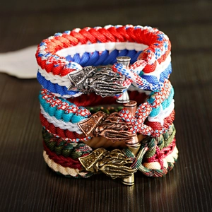 Three-piece paracord survival bracelets with vintage metal squid head buckle on wood background
