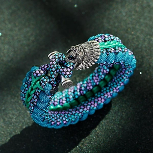 Dettaglio di bracciale in paracord intrecciato con ciondolo teschio d'argento e chiusura a levetta