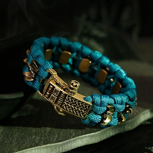 Détail d'un bracelet de survie en paracorde avec boucle en bronze sur pierre sombre