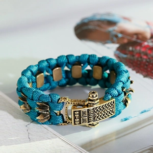 Détail macro du bracelet en paracorde tressée avec boucle en laiton et breloque en métal