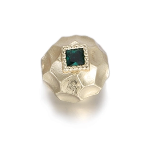 Detailed view of vintage gold bead with square green zircon and textured hammered finish