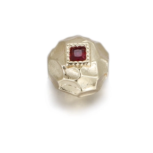 Close-up of golden hammered bead with square red gemstone and milgrain setting detail