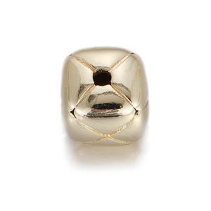 Close-up of gold geometric charm bead with cross engraving and central hole for DIY jewelry