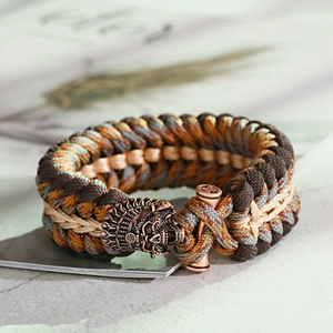 Dettaglio macro del bracciale in paracord intrecciato a mano con chiusura in bronzo antico