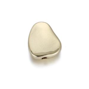 Close-up of golden irregular pebble bead with threading hole for DIY jewelry making