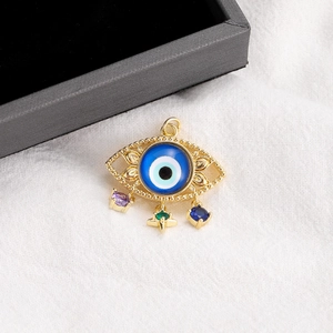Macro view of 14K gold plated evil eye pendant with colorful dangling gemstones
