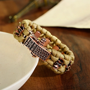 Détail d'un bracelet de survie en paracorde kaki avec boucle en bronze vintage sur bol
