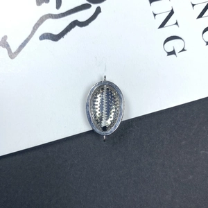 Detalle de un colgante de concha plateada con circonitas engastadas para joyería DIY