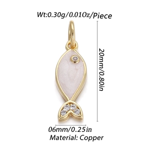 Détail macro d'un pendentif en forme de poisson en cuivre doré avec émail blanc et zircons