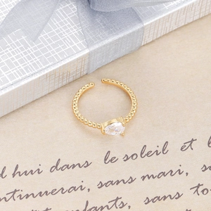 Vista macro del anillo ajustable dorado con una piedra de circón transparente de pera