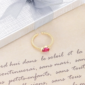 Detalle de un anillo dorado con circón rojo de pera sobre un fondo de regalo vintage