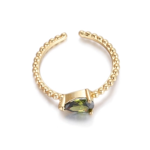 Primer plano detallado de anillo dorado con gema verde de pera y banda con cuentas