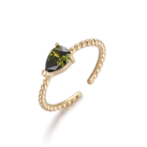 Detalle de anillo con gema verde oliva en forma de pera y banda de cuentas doradas