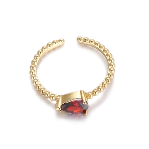 Primer plano de anillo dorado de cuentas con circón rojo gota de agua y diseño ajustable