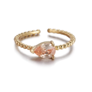 Primer plano de una circona champán en forma de pera en un anillo trenzado dorado