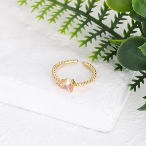 Detalle de anillo con circón champagne en forma de pera y banda dorada de perlas