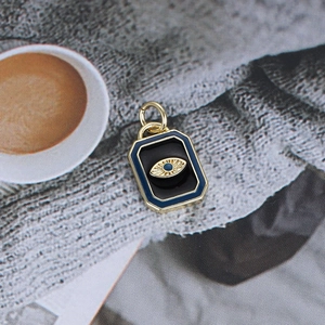 Detailed close-up of a gold rectangular evil eye pendant with blue and black enamel inlay