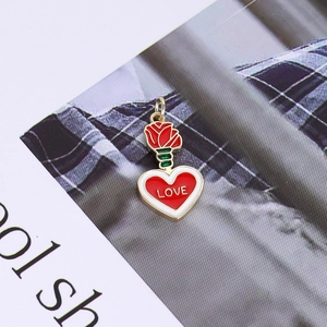 Detailed view of a 14K gold plated rose and red heart pendant with LOVE engraving