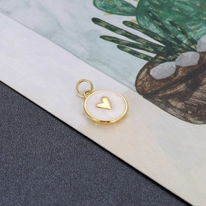 Detailweergave van een ronde gouden bedel met roze emaille en 3D-hart voor DIY-sieraden