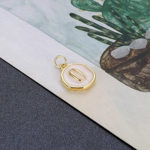 Detailopname van gouden emaille schelphanger met crème afwerking en stevig oogje