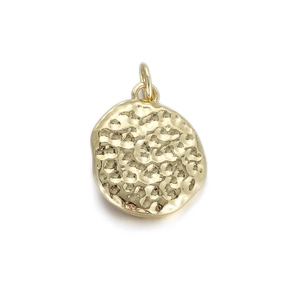 Macro-opname van de onregelmatige gouden hanger met gehamerde textuur en metalen ring