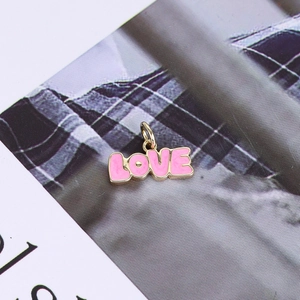Detail view of 14K gold plated heart LOVE pendant with pink enamel on magazine background