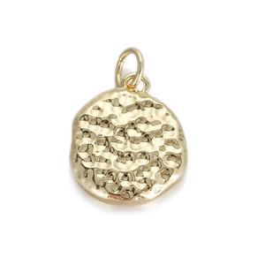 Detail van een ronde gouden hanger met gehamerde textuur en vintage metalen afwerking