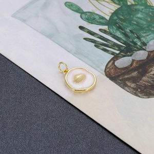 Detail van een roze emaille schelphanger met vergulde DIY-ringconnector voor sieraden