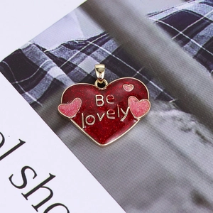 Close-up of red glitter heart pendant with Be Lovely engraving and gold plating