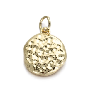 Detail van een gouden gehamerde metalen hanger met textuur voor sieraden