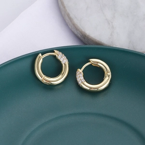 Dettaglio di orecchini a cerchio in zircone oro su vassoio in ceramica verde e marmo