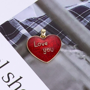 Macro detail of red glitter heart pendant with golden Love you script and bail