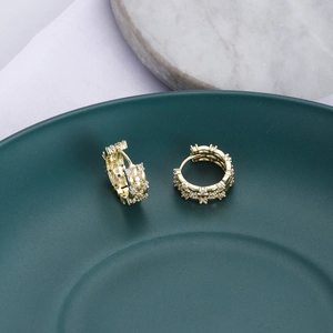 Dettaglio di orecchini a cerchio dorati con zirconi cubici scintillanti micro-pave