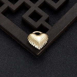Macro view of gold-plated heart pendant with radial texture and shell-like metal finish