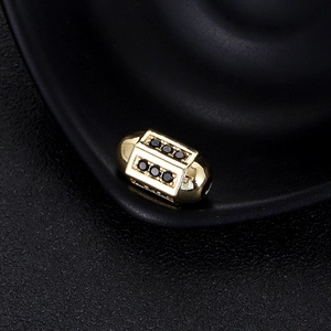 Vue macro d'une perle barillet dorée à l'or 14K avec zircons noirs pour bijoux DIY