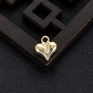 Close-up of polished 14k gold heart charm on dark wooden lattice background