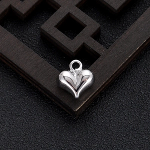 Macro shot of polished silver heart-shaped metal pendant on black leather surface