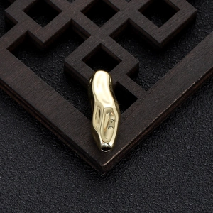 Macro detail of irregular 14k gold bean bead with high-polish finish for DIY jewelry