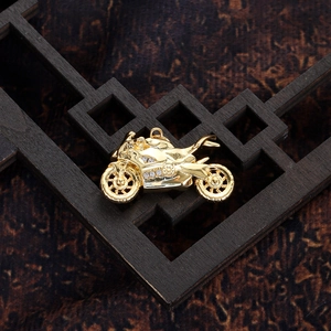 Macro detail of gold motorcycle pendant with inlaid sparkling crystals on dark wood