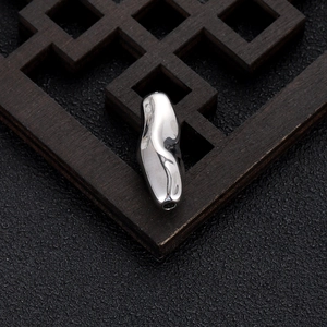 Detailed view of irregular silver bead with high-polish mirror finish and threading hole