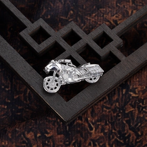 Macro shot of silver motorcycle pendant with white crystals on a rustic wood background