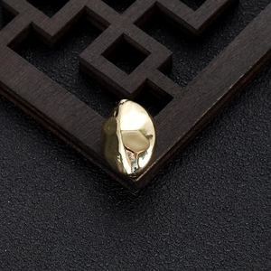 Close-up of irregular 14k gold-plated bean beads on dark wood for DIY jewelry making