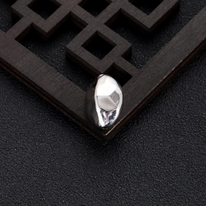Macro view of irregular silver liquid metal bead for DIY jewelry on dark zen background