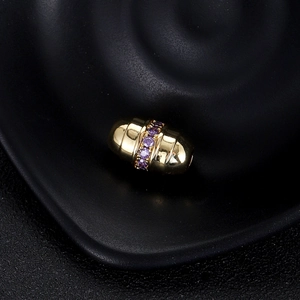 Gros plan d'une perle mauvais œil plaquée or 14K avec zircon violet sur fond noir