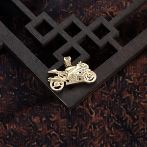 Macro view of 14K gold-plated motorcycle pendant with white crystals on vintage wood