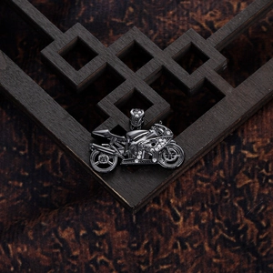 Macro view of gun black motorcycle pendant with white zircon inlays on wood