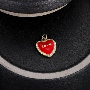 Dettaglio di un ciondolo a cuore rosso con scritta love dorata su base scura