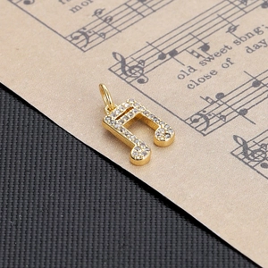 Detailed view of a gold-plated musical note pendant with sparkling zircon inlays